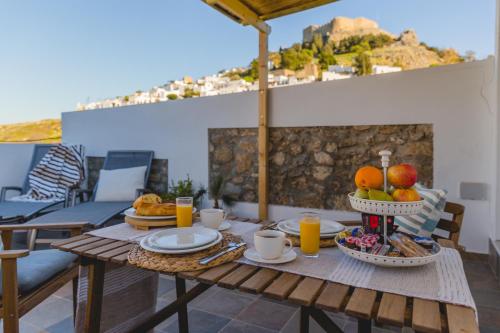 a table with food and fruit on top of a patio at Lindos SeaSide Junior Apartment in Líndos