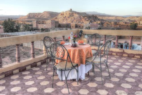 a table and chairs on a balcony with a view at Kasbah Valentine in Aït Ben Haddou