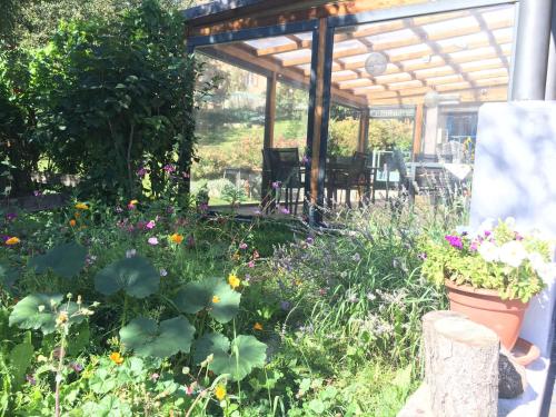 a garden with flowers and a wooden pergola at Garni Enrosadira in Vigo di Fassa
