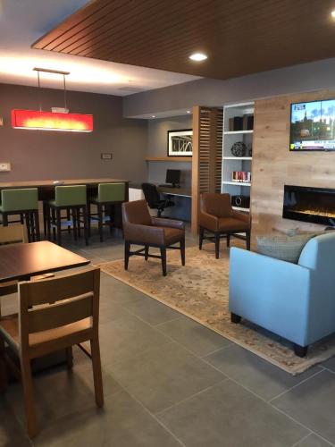 a waiting room with tables and chairs and a fireplace at Country Inn & Suites by Radisson, Novi, MI in Novi