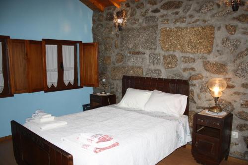 um quarto com uma cama e uma parede de pedra em Casa de Pedra em Viseu