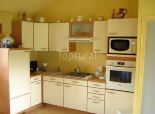 a kitchen with white cabinets and a microwave at La Ferme Pillet in Berville
