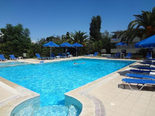 une grande piscine avec des chaises et des parasols bleus dans l'établissement Francisco Beach Hotel, à Áyios Andréas Messinias