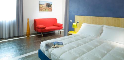 a bedroom with a bed and a red chair at Hotel Intervallo in Torre Lapillo