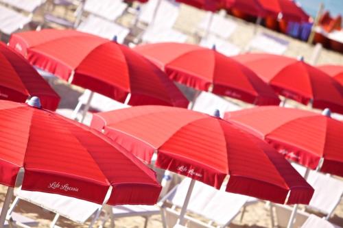 a bunch of red umbrellas sitting on a beach at Hotel Intervallo in Torre Lapillo