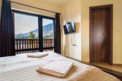 a bedroom with a bed with a balcony with a television at Pensiunea Lac Colibita in Colibiţa