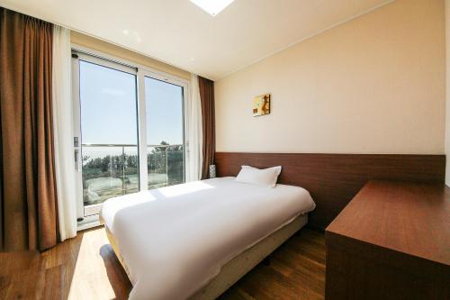 เตียงในห้องที่ Jeju Jungmun Ocean Blue Hotel