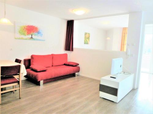 a living room with a red couch and a table at Garni B&B Apartments Plank in Nova Levante