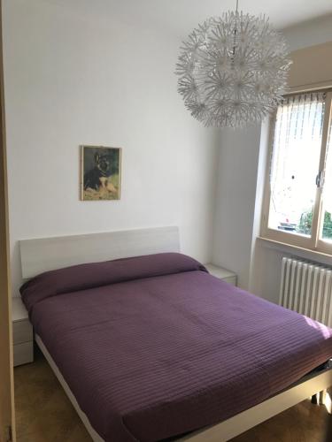 a bedroom with a purple bed and a chandelier at Casa del Faggio Rosso in Bellagio