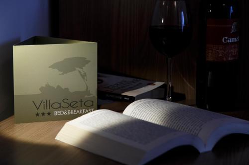 a book sitting on a table next to a glass of wine at B&B Villa Seta in Agrigento