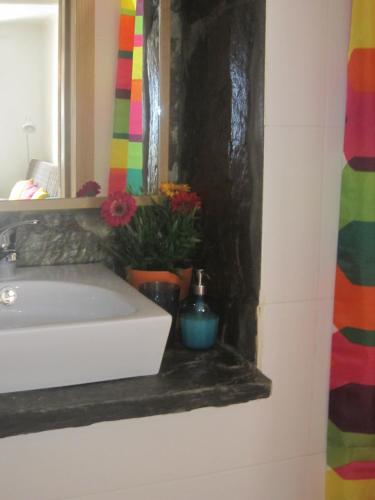 a bathroom with a sink and a mirror and flowers at Casas Botelho Elias in Pinhão