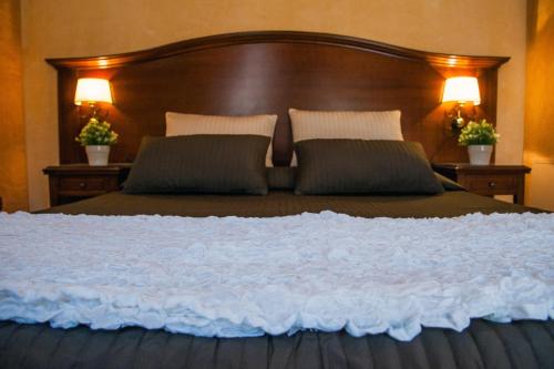 a large bed with a wooden headboard and two lamps at Hotel Al Ritrovo in Piazza Armerina