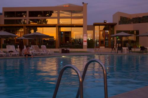 a swimming pool with chairs and a building at Casa Andina Standard Chincha in Chincha Alta