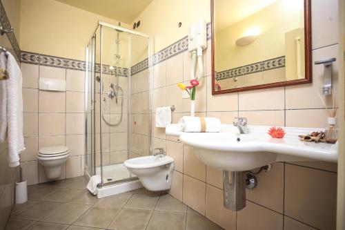 a bathroom with a sink and a shower and a toilet at Corte Fiorita Albergo Diffuso in Bosa