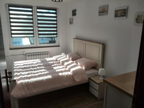 a bedroom with a bed and a window with shutters at Mikołajki Apartamenty Rynek in Mikołajki