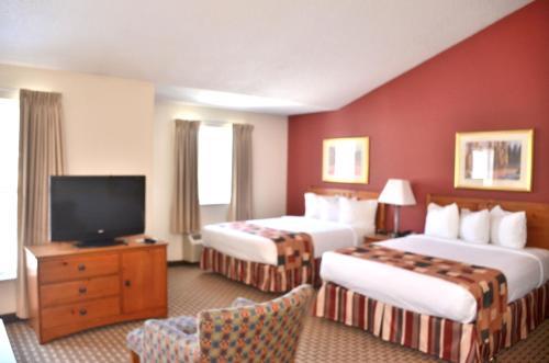 a hotel room with two beds and a flat screen tv at Cresthill Suites Syracuse in East Syracuse