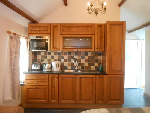 uma cozinha com armários de madeira e um lavatório em Lletygwilym, Heol dwr em Kidwelly