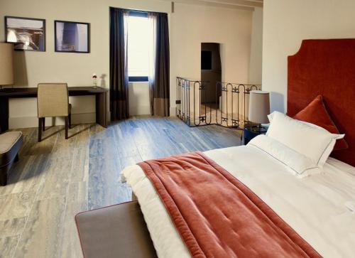 een hotelkamer met een groot bed en een bureau bij Podere Castel Merlo Resort in Villongo SantʼAlessandro