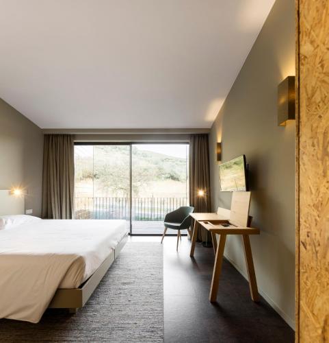 a hotel room with a bed and a desk and a window at Longroiva Hotel Rural in Longroiva