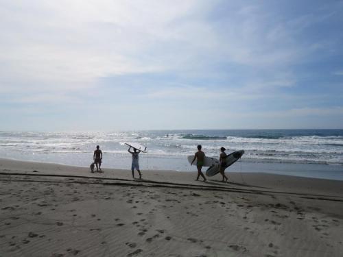 a group of people walking on the beach with surfboards at Tamowan in Donghe