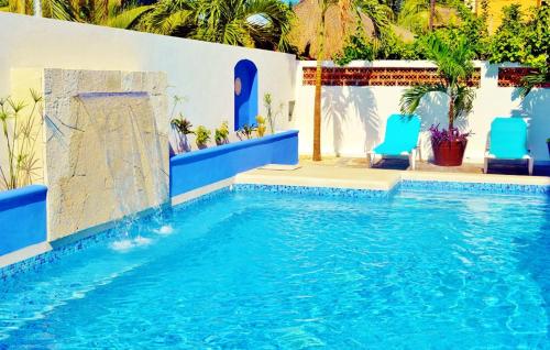 a pool with blue chairs and a swimming pool at Corales Suites in Puerto Morelos