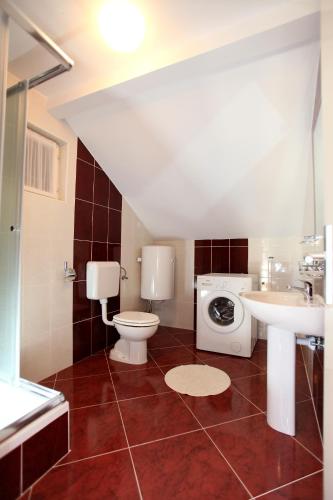 a bathroom with a toilet a sink and a washing machine at Apartment Ivan in Vinišće