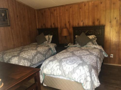 two beds in a room with wooden walls at Big Cypress in Lake Panasoffkee