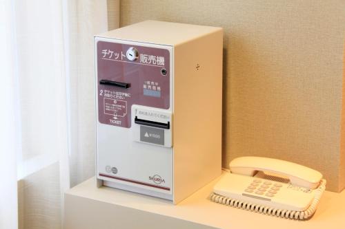 a machine with a hair dryer on a shelf at Richmond Hotel Sapporo Ekimae in Sapporo