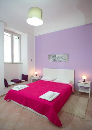 a purple bedroom with a large bed with a red blanket at Casa del Clown in Trapani