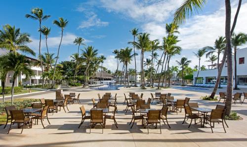 a patio with tables and chairs and palm trees at Occidental Punta Cana - All Inclusive in Punta Cana