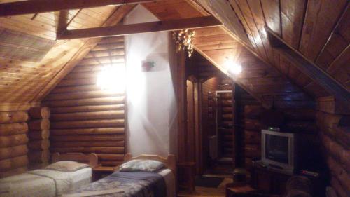 a room in a log cabin with a tv and a room at Vecskrīveri in Dundaga
