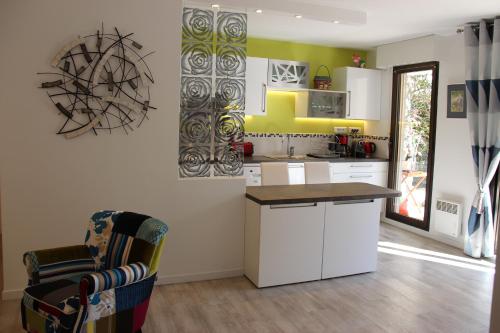 une cuisine avec des placards blancs, un comptoir et une chaise dans l'établissement Central avec Jardin, à Cannes