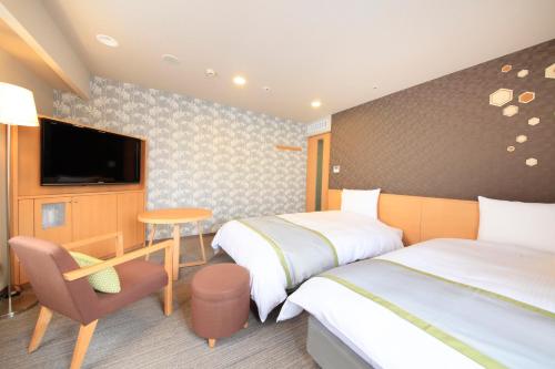 a hotel room with two beds and a television at Richmond Hotel Sapporo Ekimae in Sapporo