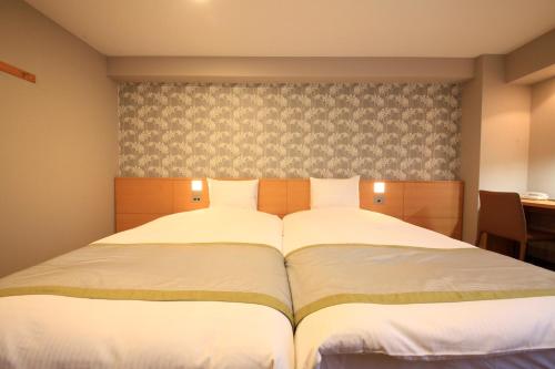a bedroom with a large bed with white sheets at Richmond Hotel Sapporo Ekimae in Sapporo