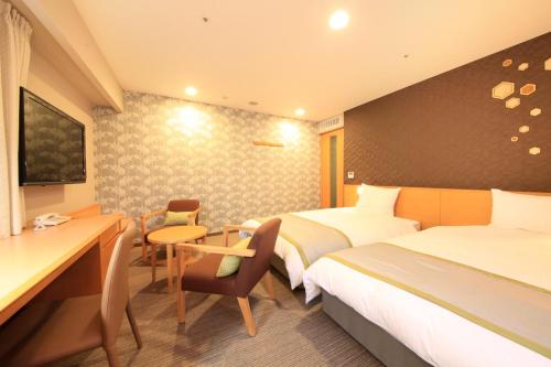 a hotel room with two beds and a desk at Richmond Hotel Sapporo Ekimae in Sapporo