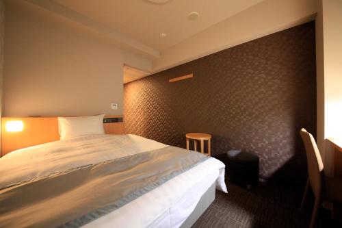a bedroom with a bed and a wall at Richmond Hotel Sapporo Ekimae in Sapporo