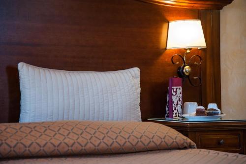 a bed with a white pillow and a table with a lamp at Hotel Al Ritrovo in Piazza Armerina
