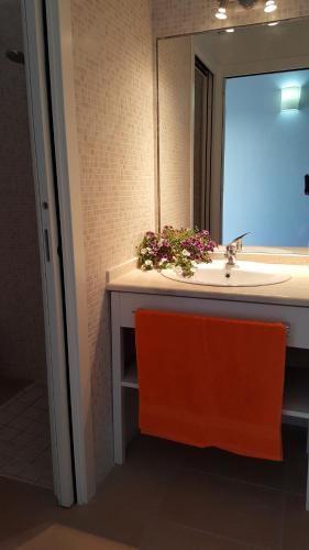 een badkamer met een wastafel, een spiegel en een oranje stoel bij Casa con ampio giardino Sulcis in Giba