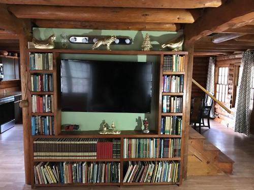 a television in a living room with book shelves filled with books at Mountain Trail Lodge and Vacation Rentals in Oakhurst