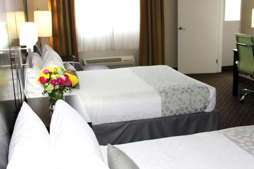 a hotel room with two beds and a vase of flowers at Best Western PLUS La Mesa San Diego in La Mesa