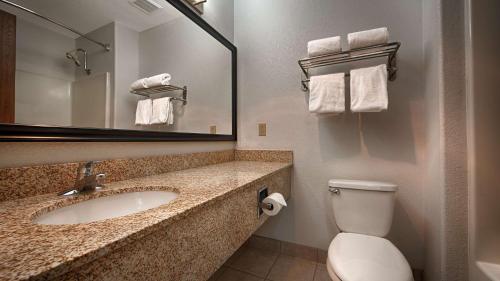 a bathroom with a sink and a toilet and a mirror at Best Western Parker Inn in Parker