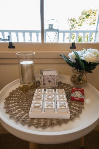 a white table with a vase of flowers and a candle at Bellevue Boutique Lodge in Taupo