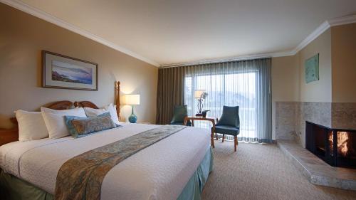 een hotelkamer met een groot bed en een open haard bij Carmel Bay View Inn in Carmel