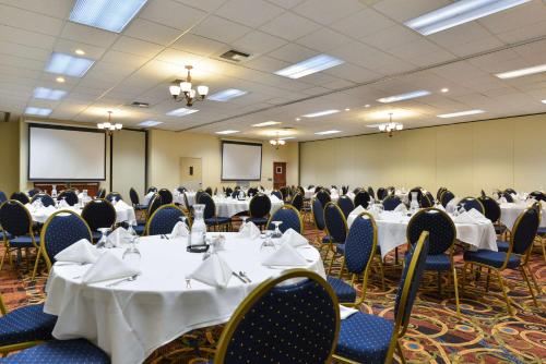 a conference room with tables and chairs and a screen at Rock Island Inn & Suites Marshalltown in Marshalltown
