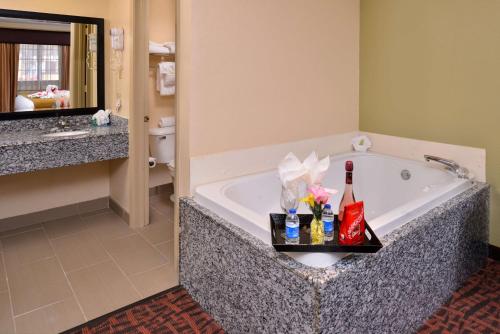 La salle de bains est pourvue d'une baignoire fleurie et d'un lavabo. dans l'établissement Best Western Eunice, à Eunice