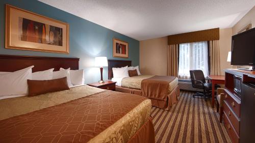 a hotel room with two beds and a flat screen tv at Best Western Plus Sikeston in Sikeston