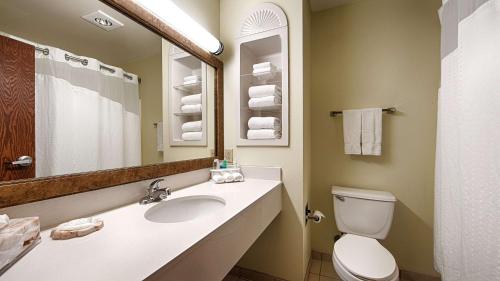 a bathroom with a sink and a toilet and a mirror at Best Western Plus Sikeston in Sikeston