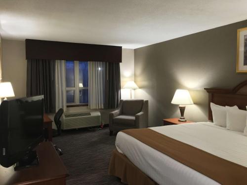 a hotel room with a bed and a chair and a television at Best Western Gateway Adirondack Inn in Utica