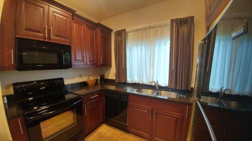 a kitchen with wooden cabinets and a sink and a microwave at Best Western Salbasgeon Inn & Suites in Reedsport