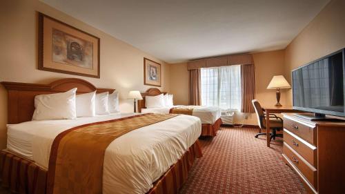 a hotel room with two beds and a flat screen tv at Best Western Casa Villa Suites in Harlingen